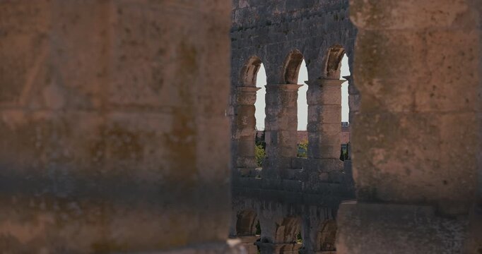 View of the stone arches inside the ancient Pula Arena Roman amphitheater framed by blurred stone columns in Pula Croatia.