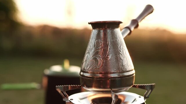 Heating Water In A Cezve On A Portable Gas Stove Outdoors For Coffee At Sunset