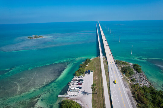 Aerial view of The Overseas Highway stretching across turquoise waters and coral reefs under a clear blue sky in Key Largo, Florida, United States.