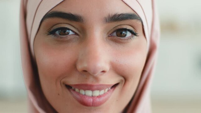 Extreme close up portrait smiling Eastern woman at home indoors Islamic girl in hijab Muslim female Arabian lady showing healthy teeth perfect skin joyful expression positive mood facial beauty inside