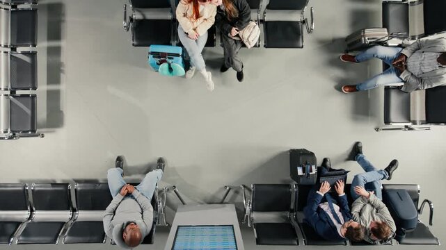 Rushing, looking at departure board screen and travelers in busy airport, top down view. Walking, flight timetable and tourists in terminal nest to people waiting for plane