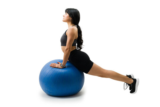Latin woman working out with stability ball doing cobra pose for core strength and flexibility on white background