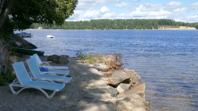 Lounge chairs in the shade on a sandy beach during a warm summer day. Lac Simon, a beautiful recreational lake in Duhamel, Quebec, Canada.