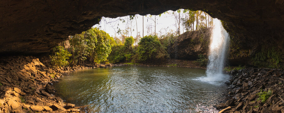 photo of waterfall over a cave and lake