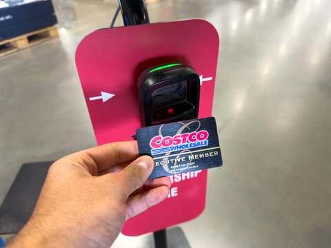 Prosper, Texas, USA - May 06, 2026: Person holding black and gold Costco Executive Membership card scanning it at digital barcode reader inside warehouse store