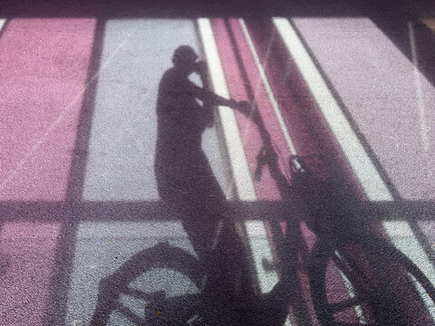 Shadow of a person with a bicycle cast on a colorful floor