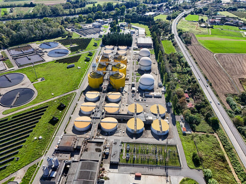 Aerial view of the Impianto depurazione water treatment plant with circular tanks, yellow digesters, and solar panels in Castiglione Torinese, Piedmont, Italy.