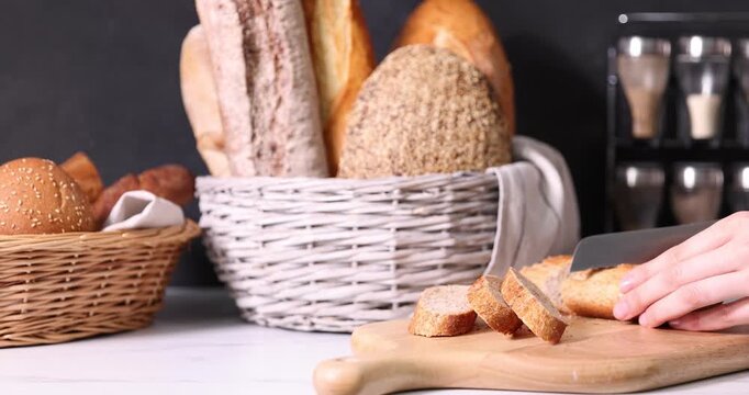 Woman cutting freshly baked bread at white countertop, closeup