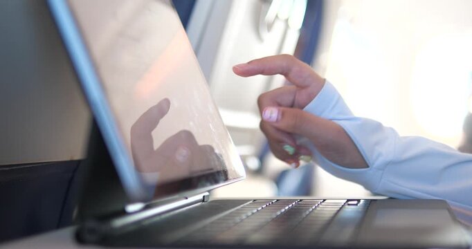Cinematic close-up of a hand touching a tablet screen on an airplane, digital in-flight entertainment and travel technology concept