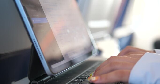 Cinematic close-up of a hand touching a tablet screen on an airplane, digital in-flight entertainment and travel technology concept