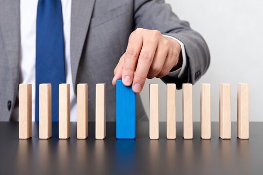 Businessman placing blue block among wooden blocks