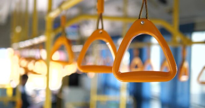 Cinematic close-up of yellow triangle handrail grips inside a public bus, blurred interior and urban transportation concept