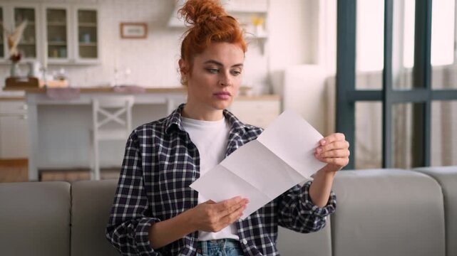 Happy shocked Caucasian woman reading good news letter at home couch smiling female opening envelope relieved glad about bank debt loan approval job offer success positive notification apartment joy