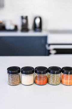tidy spices and herbs in matching jars on kitchen countertop with soft kitchen bokeh background