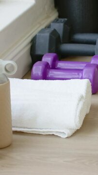 Vertical video: Recording camera framing folded towel at home, showing dumbbells before workout