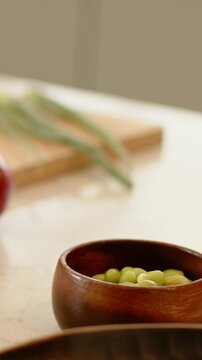 Vertical video: Panning camera showing red onion, pea bowl, avocado on kitchen counter, copy space