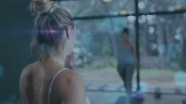 Instructor standing near glass wall raising arm, cueing yoga students lunging and building strength