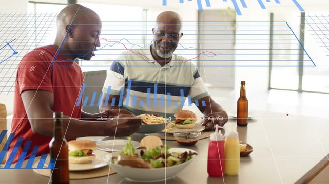 Adult man reaching and serving fries to senior man sharing meal, animated blue charts overlaying