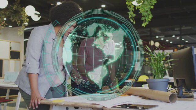 Two designers leaning over plans, globe hovering over table, right peer reaching, marking revision