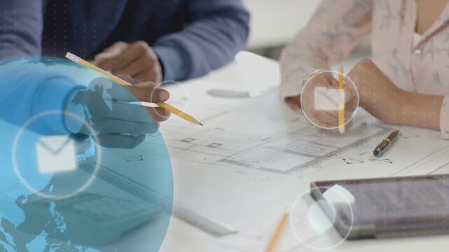 2 designers working over plans, globe appearing UI icons floating hands aligning layout for review