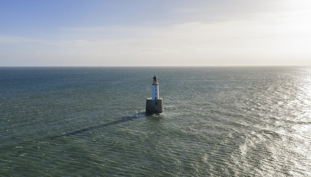 Aerial view of Rattray Head Lighthouse standing in the North Sea with gentle waves and a clear horizon Peterhead, Scotland, United Kingdom.