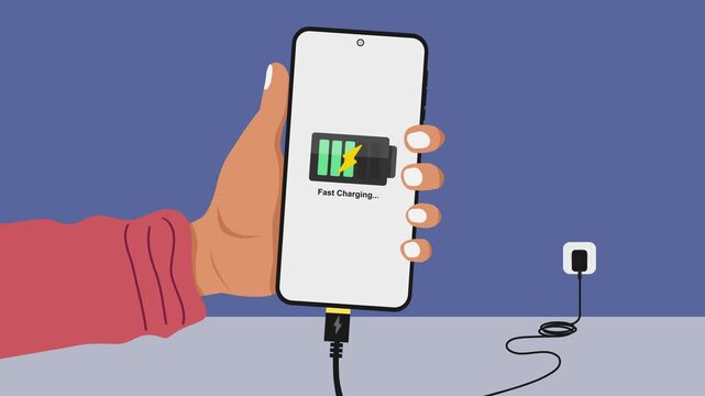 Hand holding a mobile phone while charging the battery from wall outlet