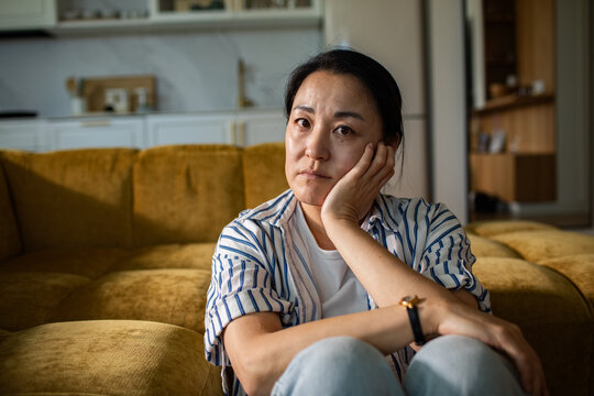 Pensive woman sitting on couch at home