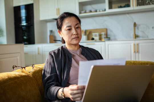 Woman reviewing bills on laptop at home