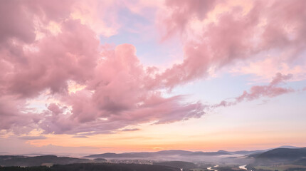 Fototapeta premium Beautiful pink clouds at sunset over a misty landscape, creating a serene and breathtaking natural panorama