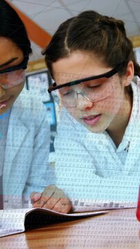 Vertical video: Two students writing notes for lab, pencil causing numeric overlay and graphs