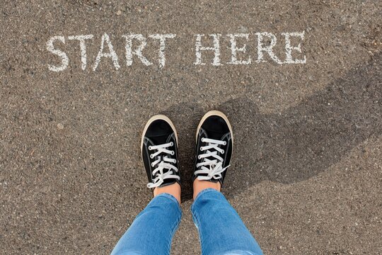 Person standing on start here marker ready for new beginning