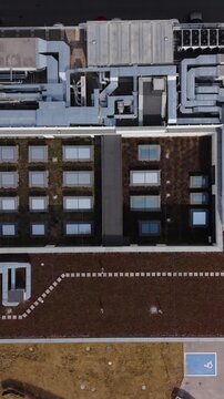 Vertical screen Aerial Commercial Rooftop Showing HVAC Arrays, Skylights, Ductwork And Maintenance Walkways, Mechanical Systems And Urban Building Services Visible From Above
