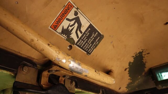 Interior of armored vehicle showing hatch warning label and controls in confined military space