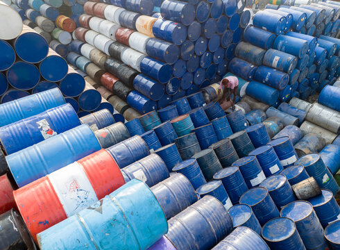 Aerial view of thousands of stacked colorful industrial barrels with a worker standing among them in Dhaka, Dhaka Division, Bangladesh.