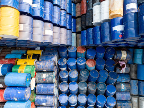 Aerial view of hundreds of colorful industrial oil barrels stacked in a storage yard with a worker standing among them Dhaka, Dhaka Division, Bangladesh.