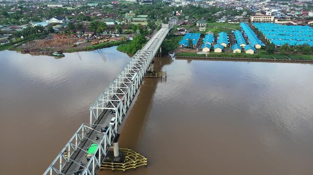 A view from the steel bridge spanning the Kapuas River in West Borneo, Indonesia, featuring the cityscape and traffic.