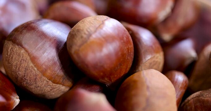 Edible chestnuts are brown in color, a handful of dried chestnuts are poured into a wooden cup that is mounted on boards with a rough texture.