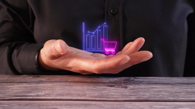Sales reports and business analysis. Close-up of a woman's hand on a table holding a virtual icon of a graph with a shopping cart.