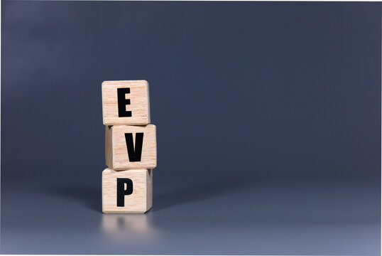 EVP acronym on wooden cubes over a dark grey background. Concept for Employee Value Proposition or Executive Vice President, business leadership, management, and corporate concepts.