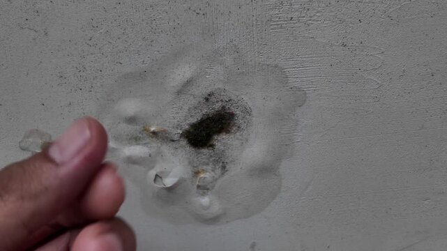 Macro footage showing a significant hole and moisture damage on a white painted concrete wall. Useful for home inspection, renovation, and construction repair themes.