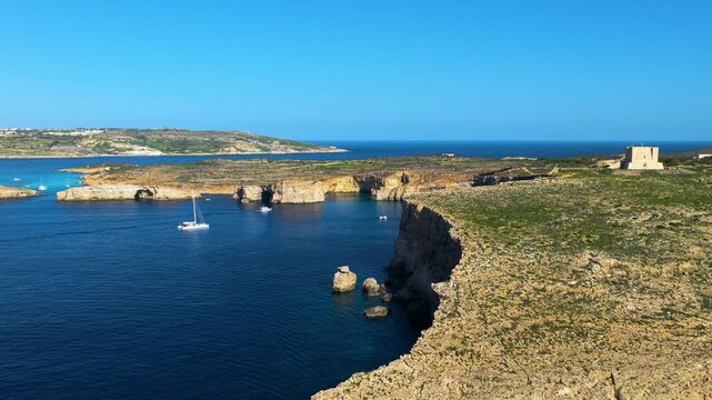 Dramatic Limestone Cliffs And Hidden Sea Caves With Catamaran Boats In Blue Lagoon On Comino Island In Malta. Aerial Shot
