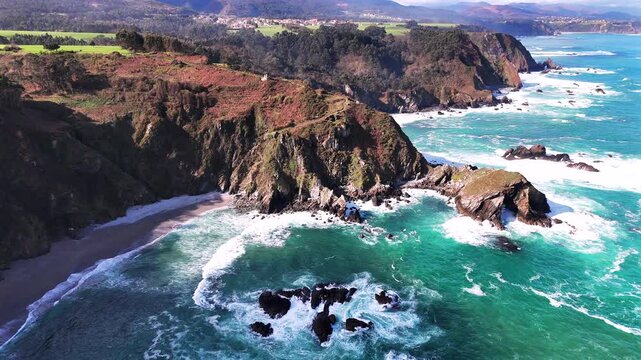 Aerial view of turquoise cove with rocky cliffs and small sandy beach.