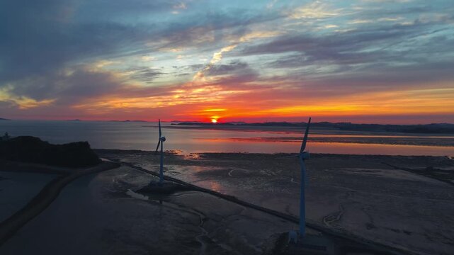 Aerial view of golden sunset over Tando Port sea road featuring wind turbines and Nue Island during low tide in Ansan South Korea