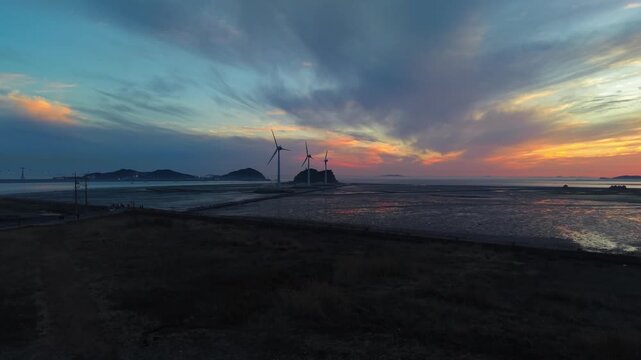 Golden sunset sky over Tando Port sea road featuring giant wind turbines and Nue Island during low tide in Ansan South Korea