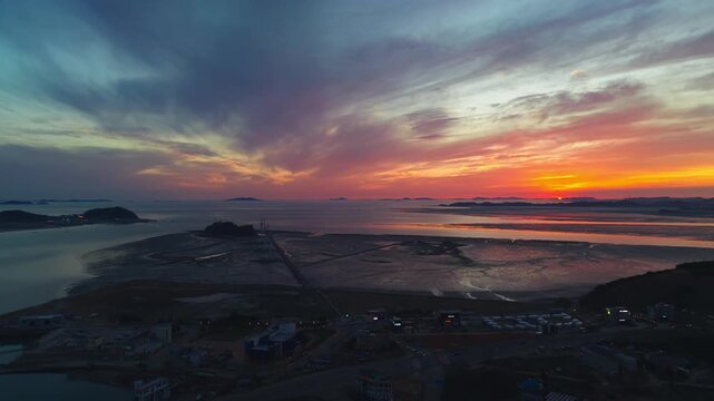 Golden sunset illuminates wind turbines along Tando Port sea road leading to Nue Island at low tide in Ansan Gyeonggi-do