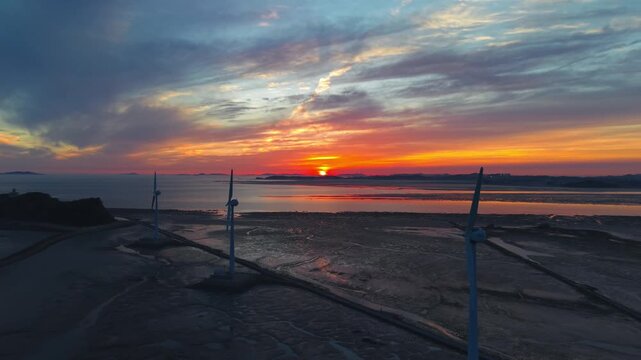 Golden sunset illuminates wind turbines along Tando Port sea road leading to Nue Island at low tide in Ansan Gyeonggi-do