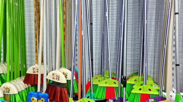Sidoarjo, Indonesia - 4 May, 2026: ​Colorful Plastic and Nylon Brooms on Retail Display Rack Household Cleaning Supplies Aisle