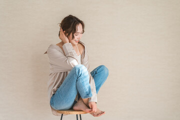Fototapeta premium A female model in denim clothing sitting on a high chair.
