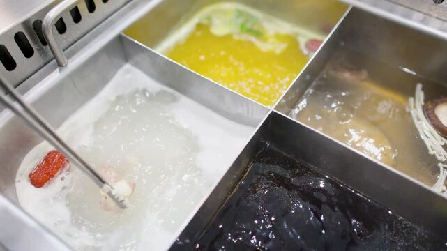 Cooking Pork Slices in Boiling Hot Pot Soup with Metal Tongs