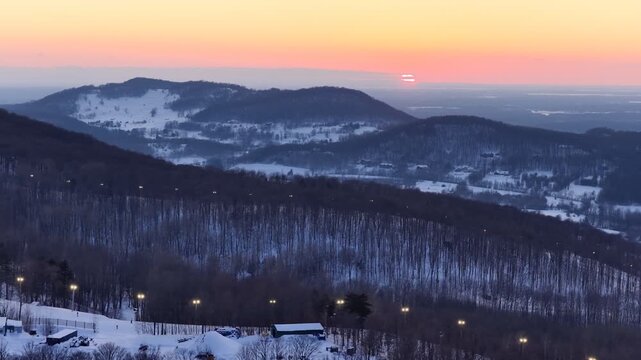 Aerial drone view of illuminated Bromont ski resort slopes at dusk, Quebec, Canada in winter. g.